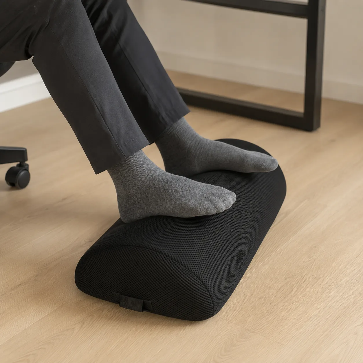 Jambes assises au bureau, pieds à plat sur le repose-pied ergonomique, genoux à angle droit